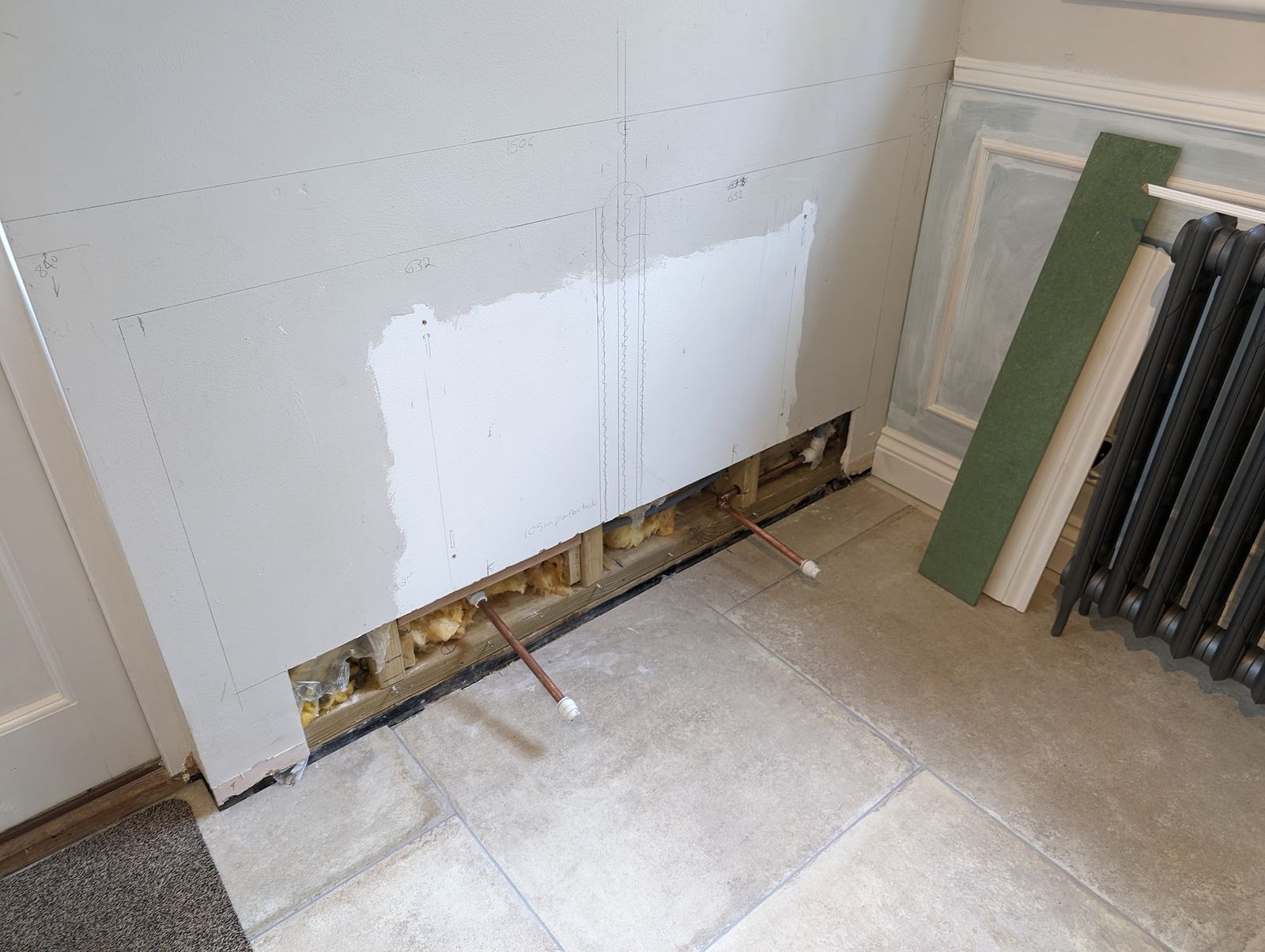 Pipework set into the wall at floor level, with a column radiator waiting to go on