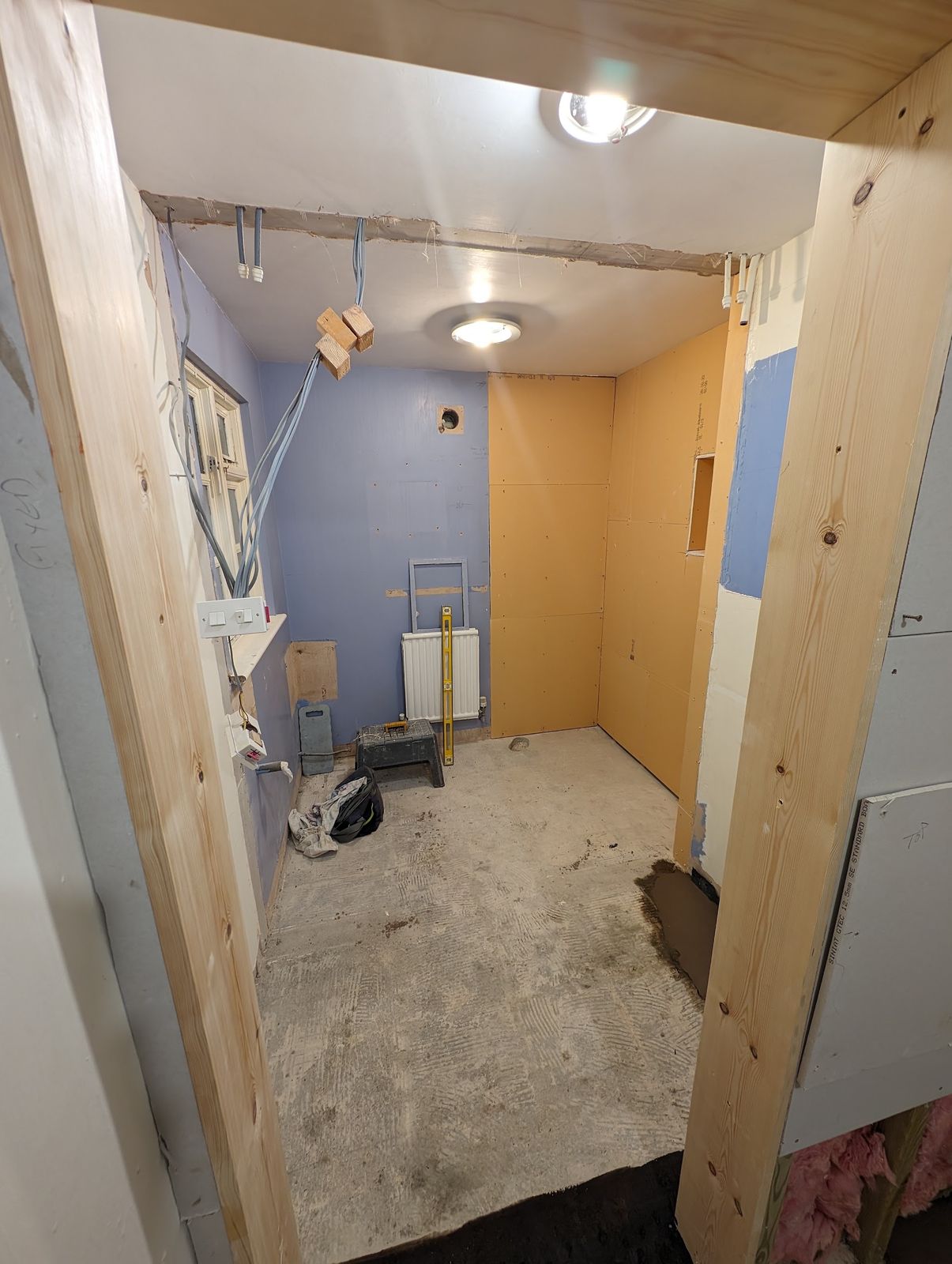 A bathroom stripped back to bare walls and floor during the work