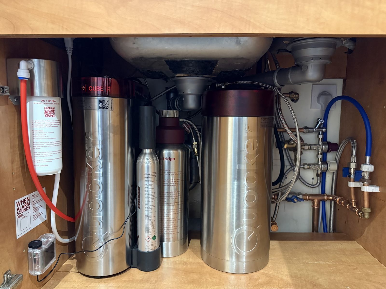 Under a kitchen sink: a Quooker tank, a Cube and a Scale R filter with neat pipework on the back wall